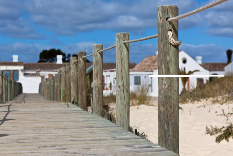 Wooden footpath through dunes at the ocean beach in Portugal